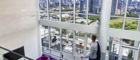 Una habitación de hotel moderna con ventanas amplias, chimenea y vista a la ciudad.