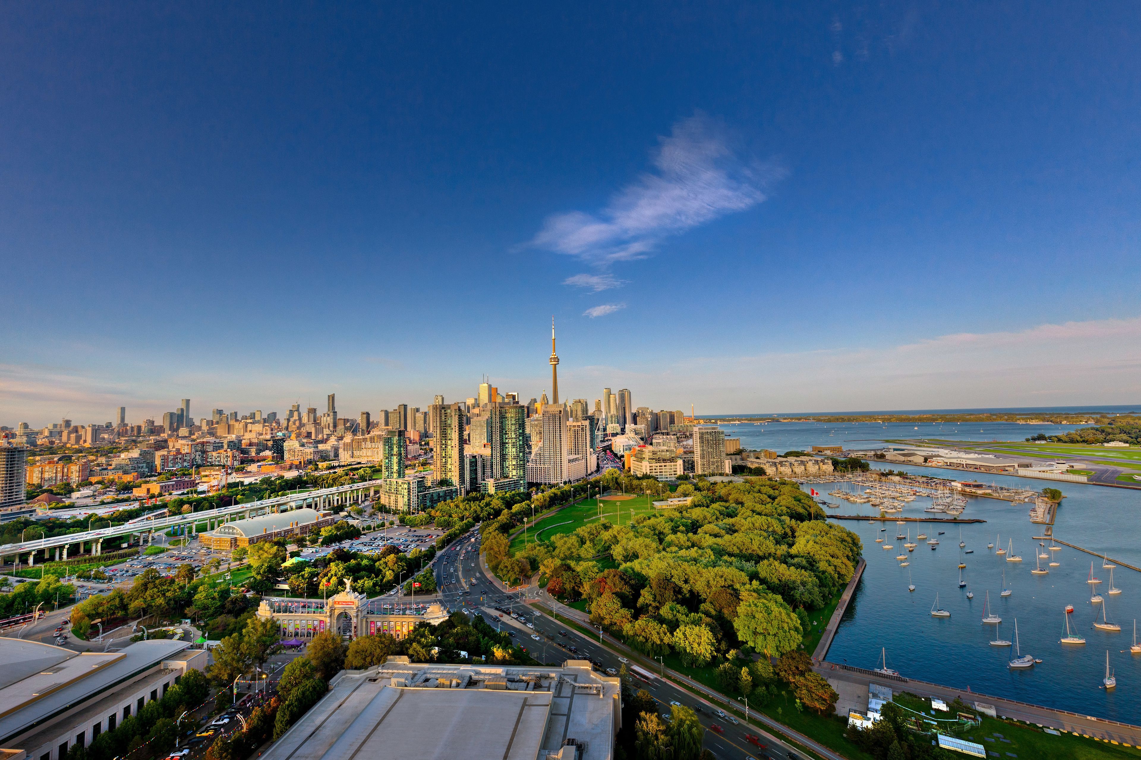 A cityscape with a prominent tower, a marina with boats, and a green park area.