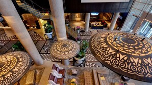 A spacious lobby with a central staircase, patterned floor tiles, and a variety of seating arrangements including sofas and chairs. - Hotel X Toronto, a Destination by Hyatt Hotel (Toronto)