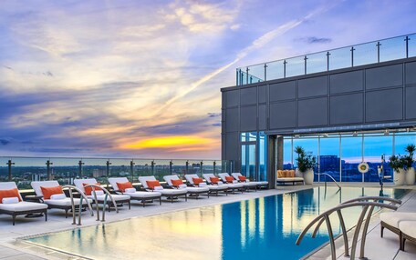 A rooftop pool with lounge chairs and a city view.