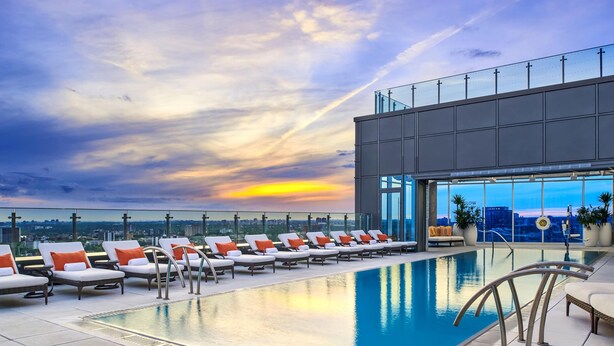 A rooftop pool with lounge chairs and a city view.