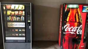 Two vending machines, one for cold drinks and another for Coca-Cola, placed against a wall.