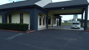 A motel with a covered parking area and a white car parked inside.