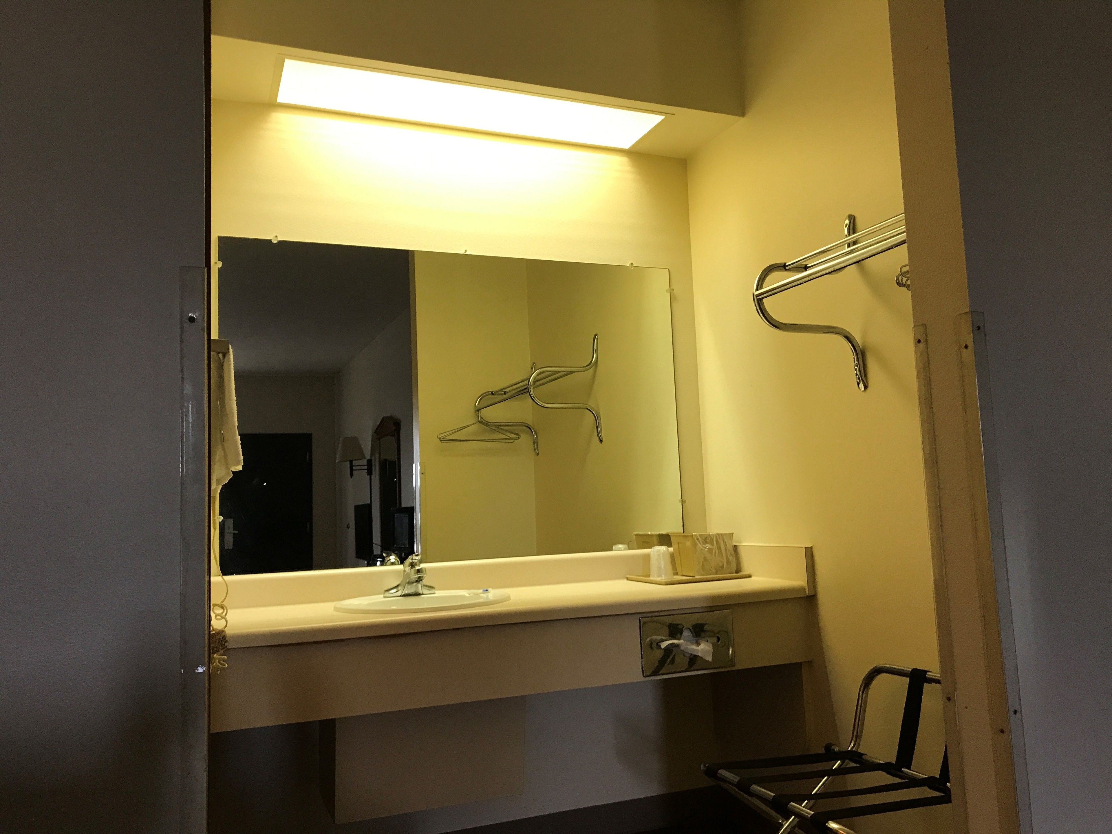 A bathroom with a mirror, sink, towel rack, and a hand dryer.