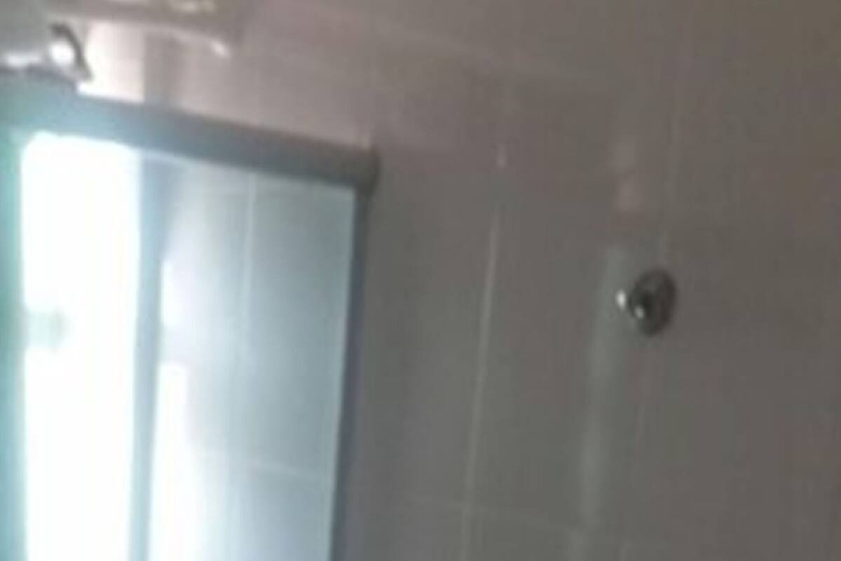 A bathroom with a toilet, a glass shower enclosure, and a white tiled wall.