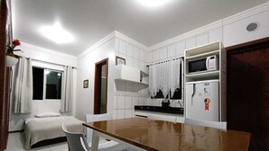 Une cuisine de taille réduite avec des meubles blancs, un four à micro-ondes et un réfrigérateur.