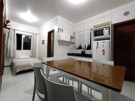 Uma cozinha compacta com armários brancos, micro-ondas e geladeira.