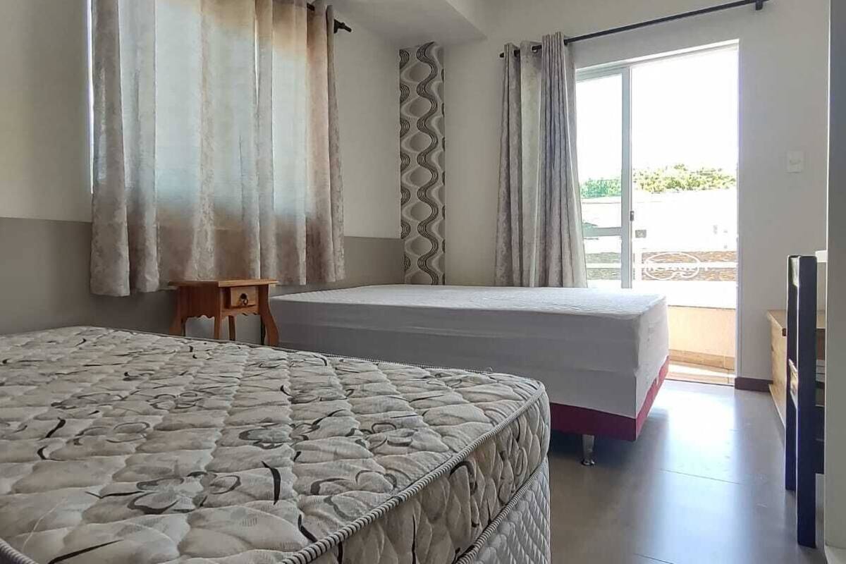 Ett sovrum med två sängar, ett litet bord och en skjutdörr i glas som leder ut till ett område utomhus.