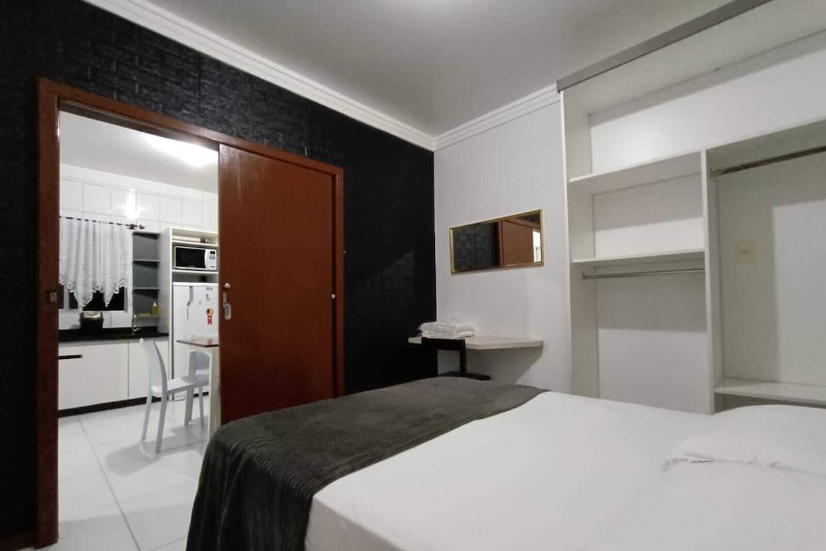 Ett hotellrum med en säng, ett skrivbord, en stol, en garderob och ett badrum.