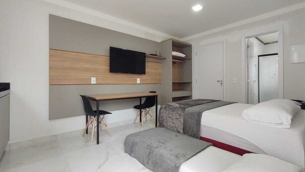 Une chambre d’hôtel moderne équipée d’un lit, d’un bureau et d’un téléviseur fixé au mur.