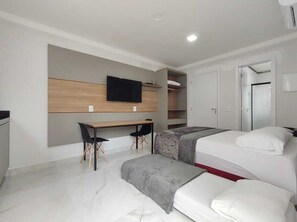 A modern hotel room with a bed, a desk, and a TV mounted on the wall. - Residencial Batista (Bombinhas)