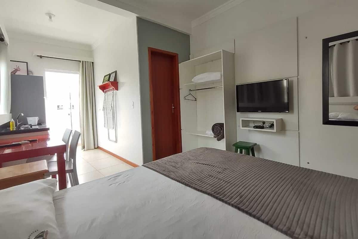 Ett hotellrum med en säng, ett skrivbord med en stol, en tv och en garderob.
