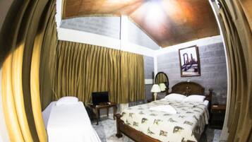 Un dormitorio con cama, escritorio, silla, lámpara y un cuadro en la pared.