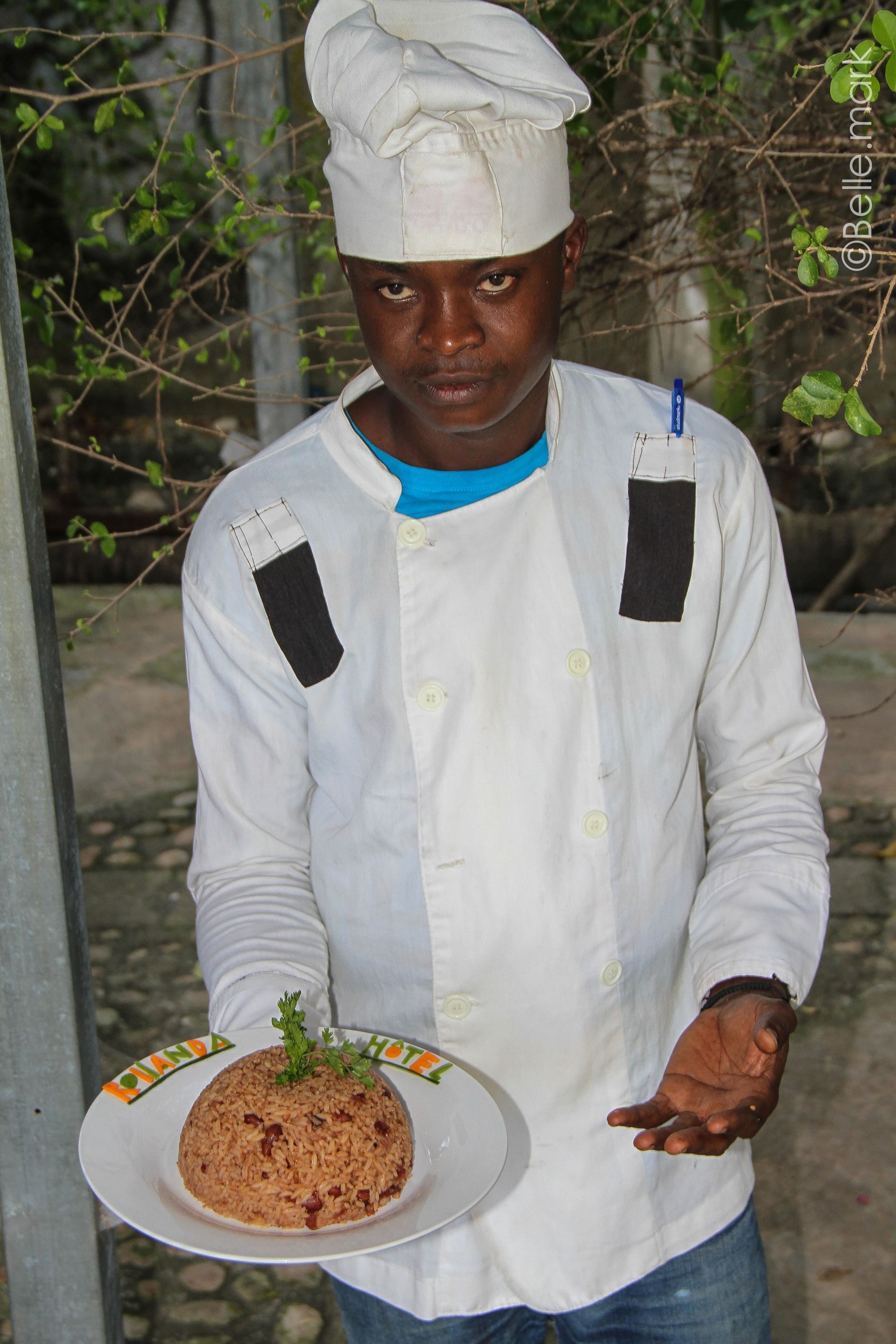 A person in a chef's uniform holding a plate of food.