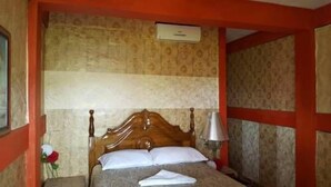 A bed with a wooden headboard, a bedside lamp, and a floral decoration on the nightstand.