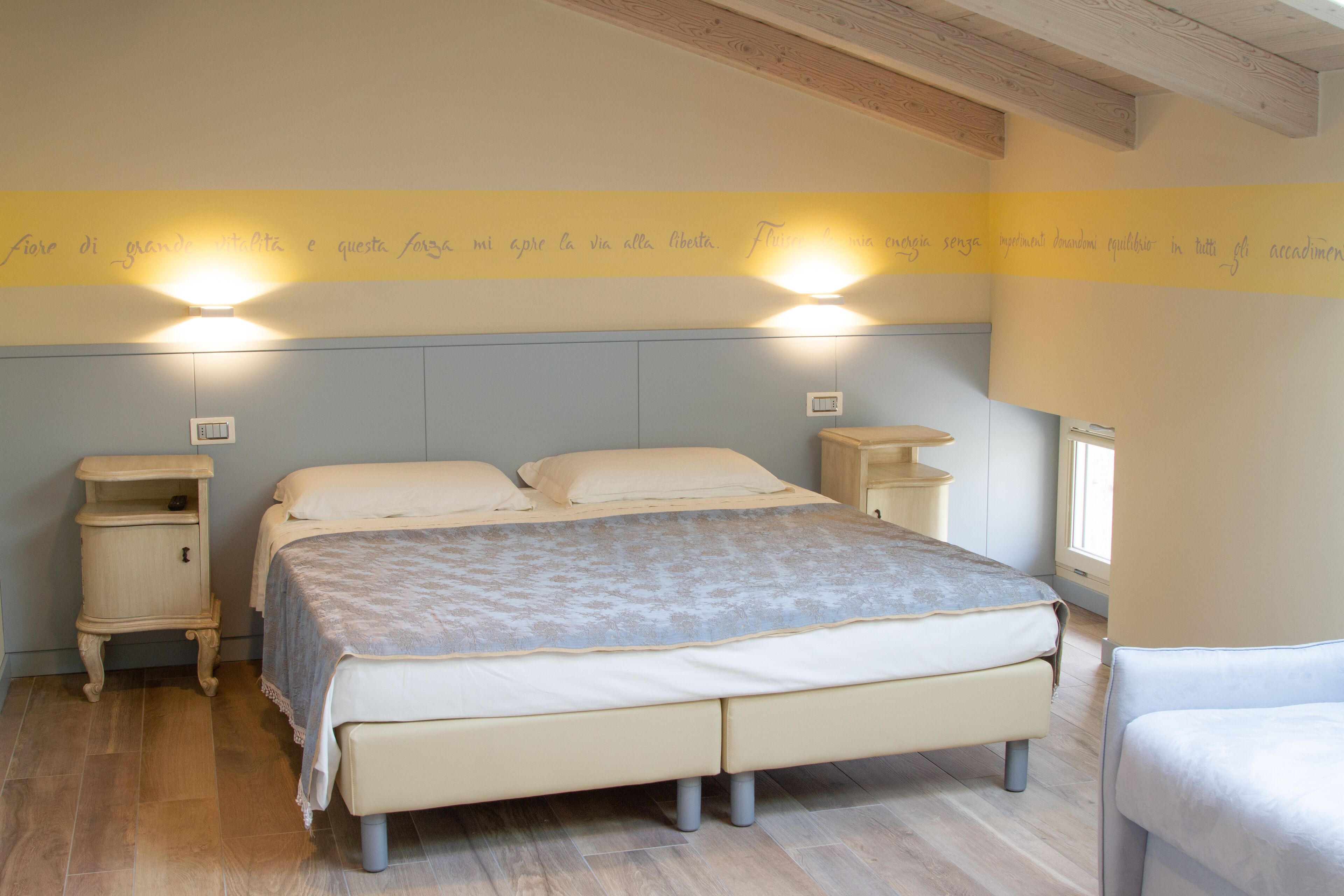 Une chambre à coucher avec un lit, des tables de chevet et un mur orné d’un panneau jaune.