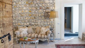 Un salon avec un mur en pierre, un canapé, une table basse et une lampe.