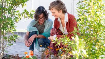 Dos personas sentadas en un patio rodeado de plantas y flores.