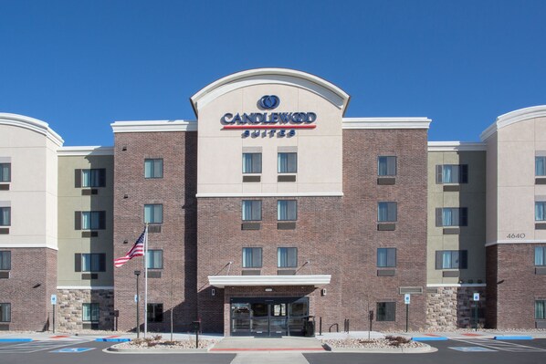 Un hotel con un llamativo letrero de "Candlewood Suites", varias ventanas y una bandera.