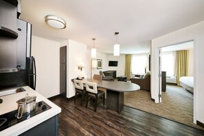 Een moderne hotelkamer met kitchenette, een eethoek en een zithoek.