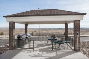 Un espacio al aire libre techado con una parrilla y asientos, con vistas a un paisaje rural.