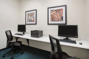 Un espacio de trabajo con dos monitores de ordenador, una impresora y dos sillas.