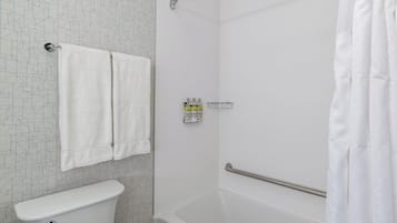 A bathroom with a toilet, a shower with a grab bar, and a towel rack.
