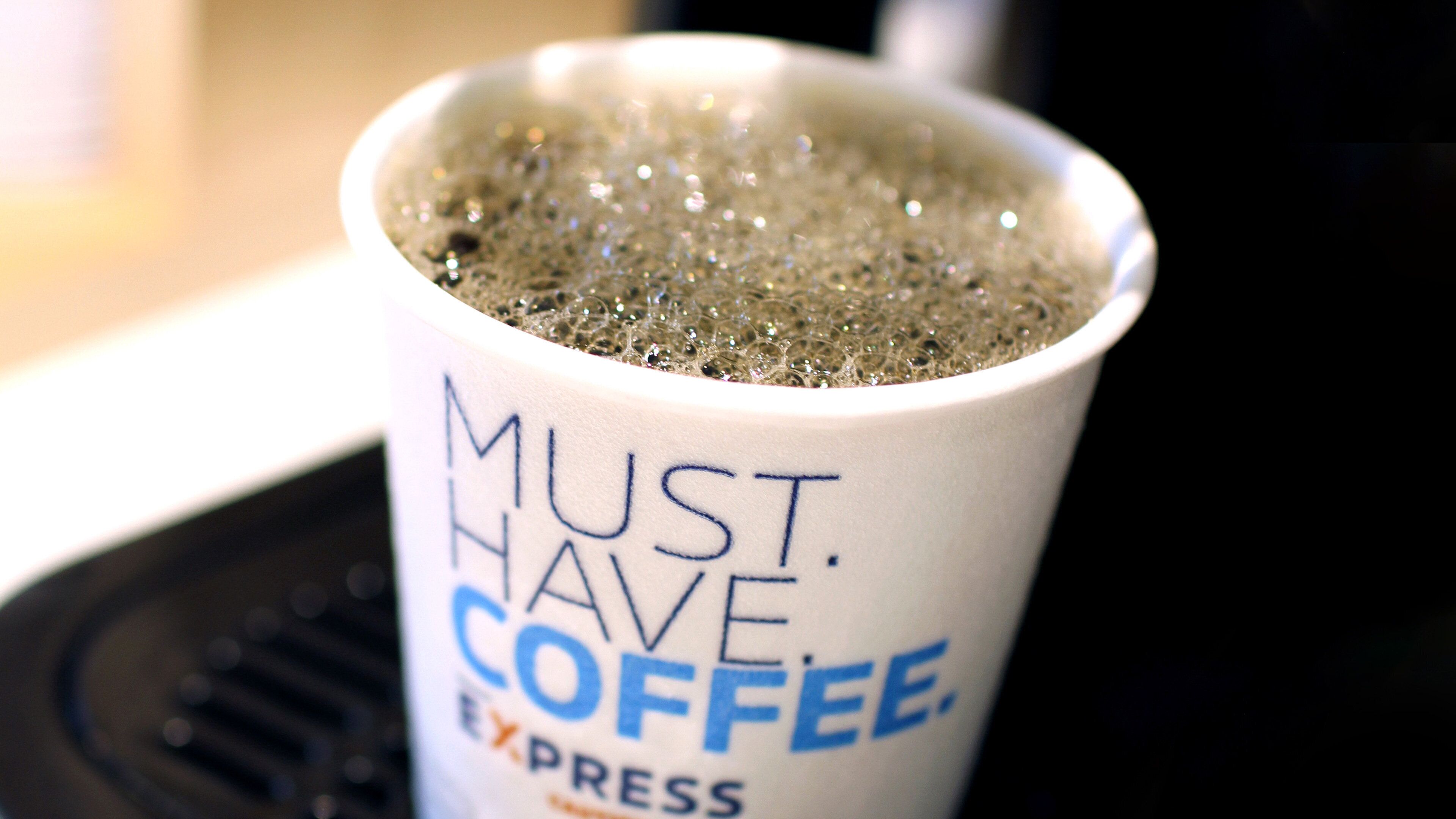 A white coffee cup with the text 'MUST HAVE COFFEE EXPRESS' on it.