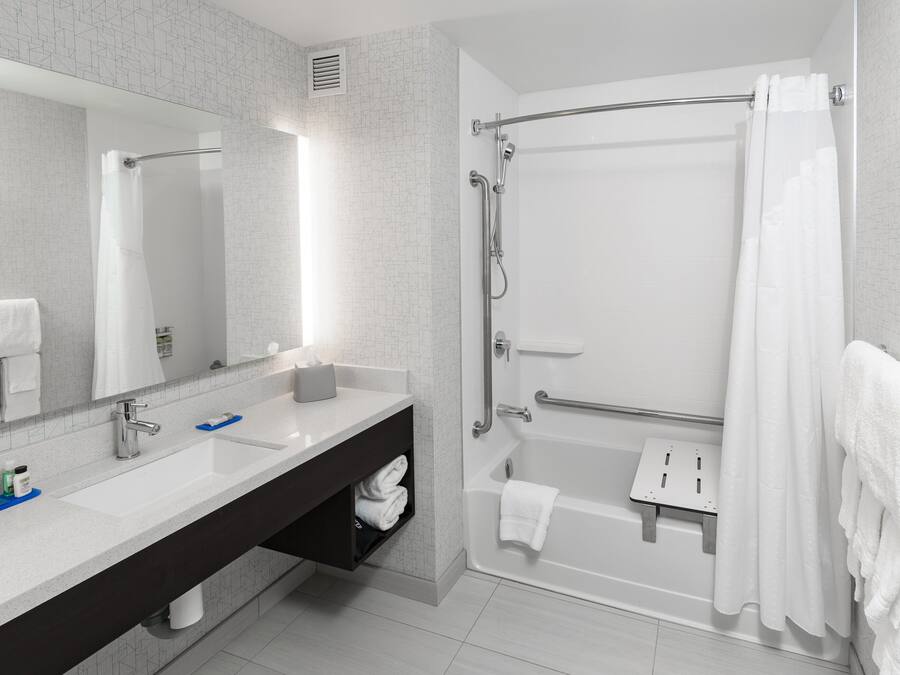 Un baño moderno con un espejo grande, dos lavamanos, una bañera y una ducha.