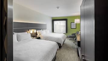 Quarto de hotel com duas camas, uma escrivaninha, uma cadeira e janela com vista.