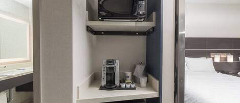 Une chambre d’hôtel dotée d’un coin cuisine comprenant un four à micro-ondes, une machine à café et des rangements.