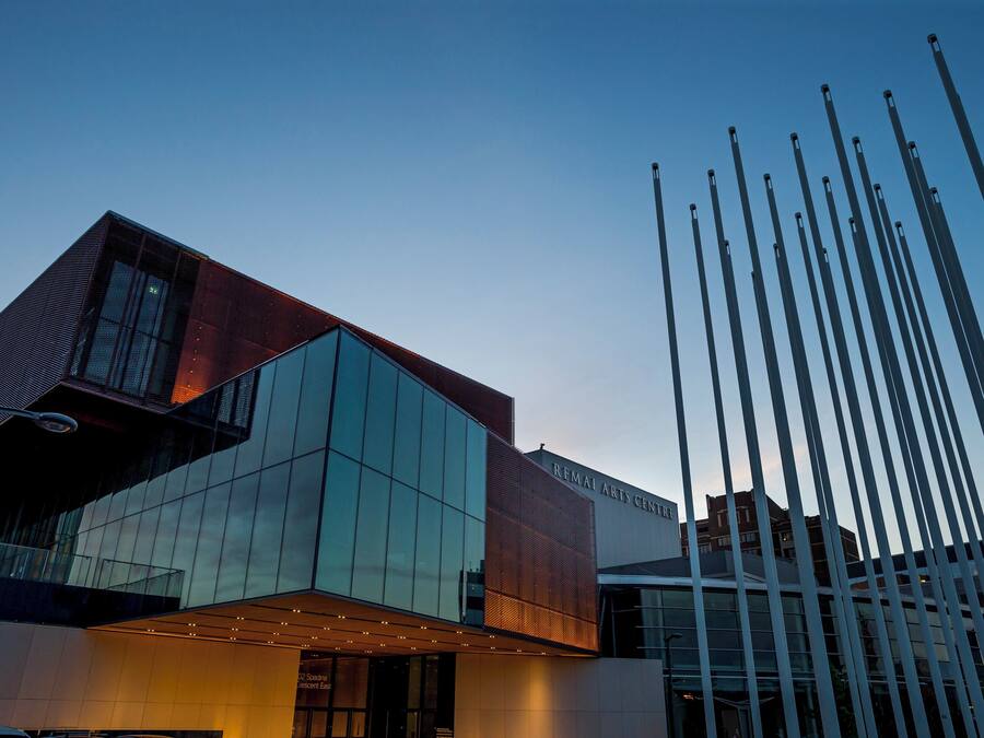 A modern building with a glass facade and a metal structure with vertical elements.