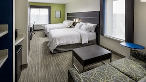 Une chambre d’hôtel avec deux lits, un bureau, une chaise, une petite table et une fenêtre.