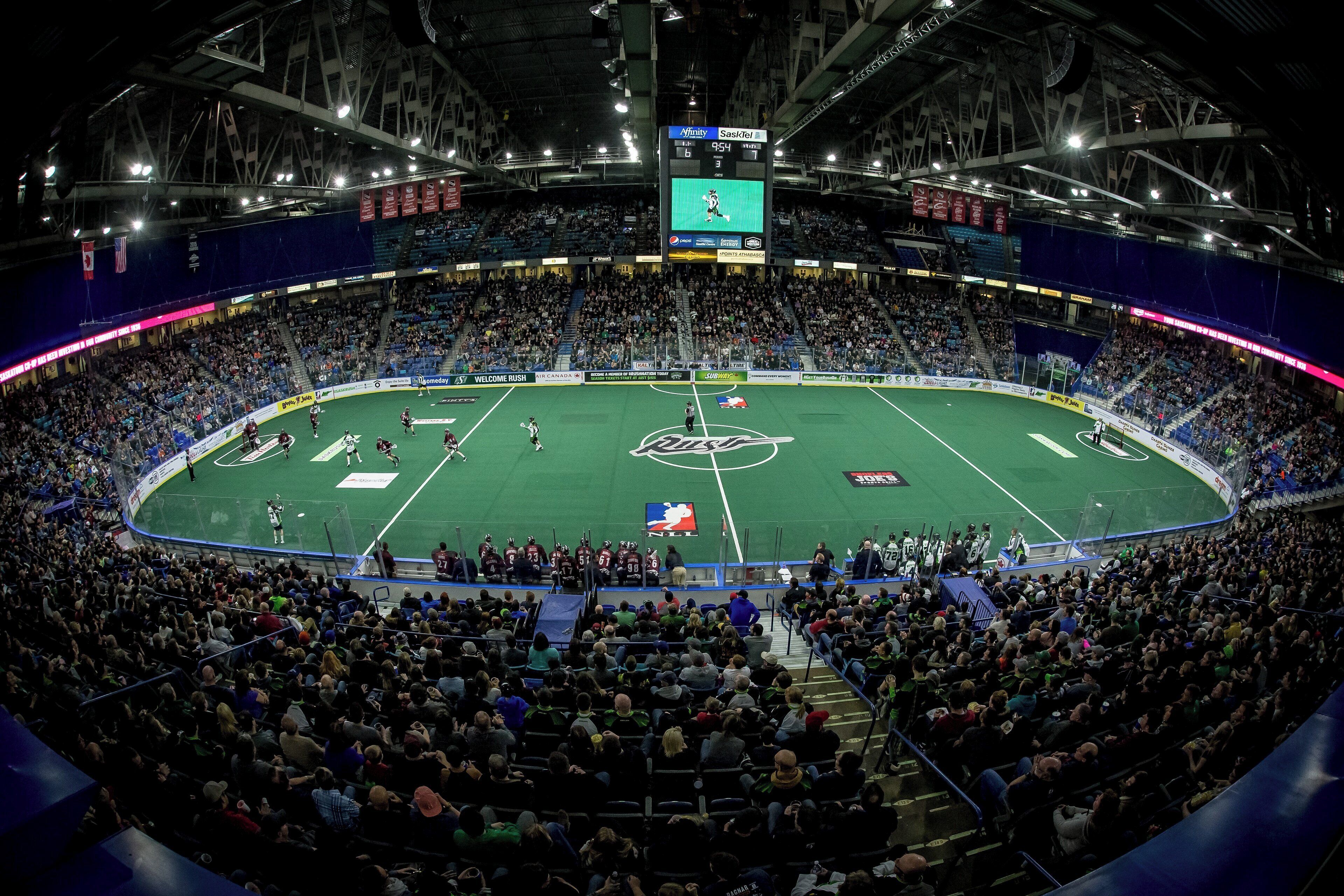 A large indoor stadium with multiple levels of seating, a central field, and a scoreboard.