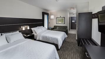 A hotel room with two beds, a desk, a chair, a TV, and a framed picture on the wall.