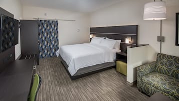 Una habitación de hotel con cama, escritorio, silla, sofá y lámpara.