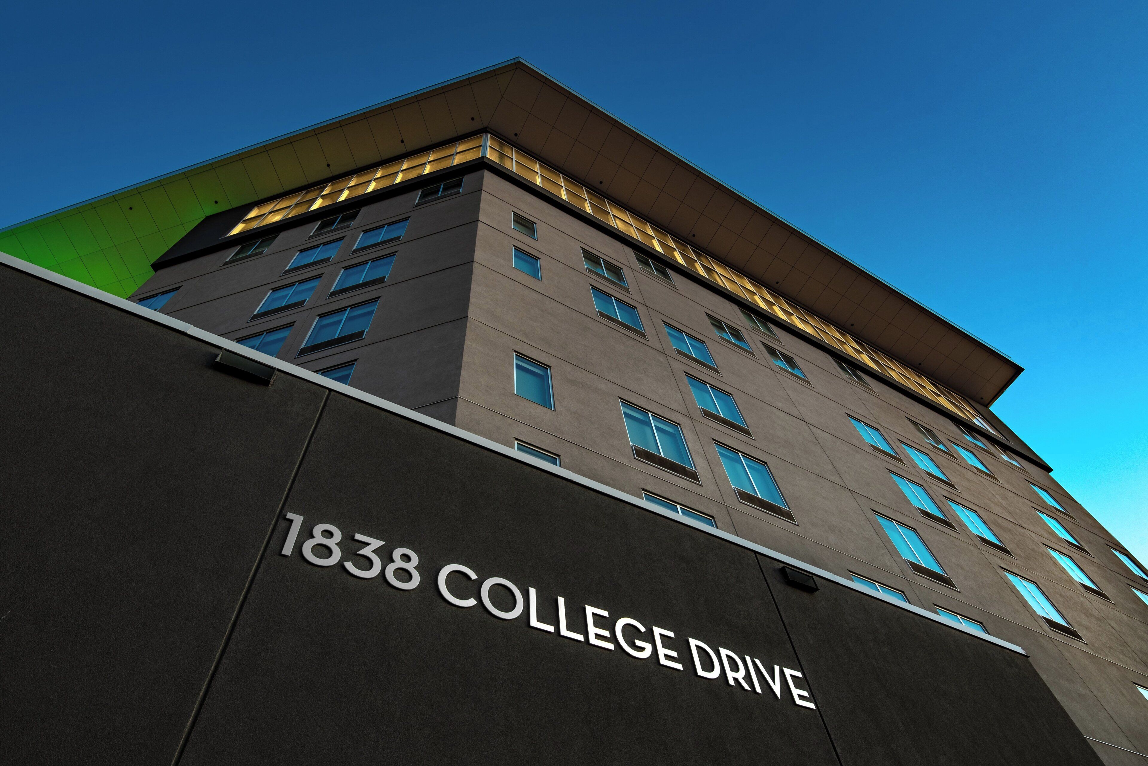 Un edificio con la dirección '1838 COLLEGE DRIVE' y varias ventanas.