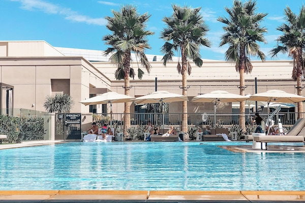 Una piscina al aire libre, camas de piscina con cargo, sombrillas