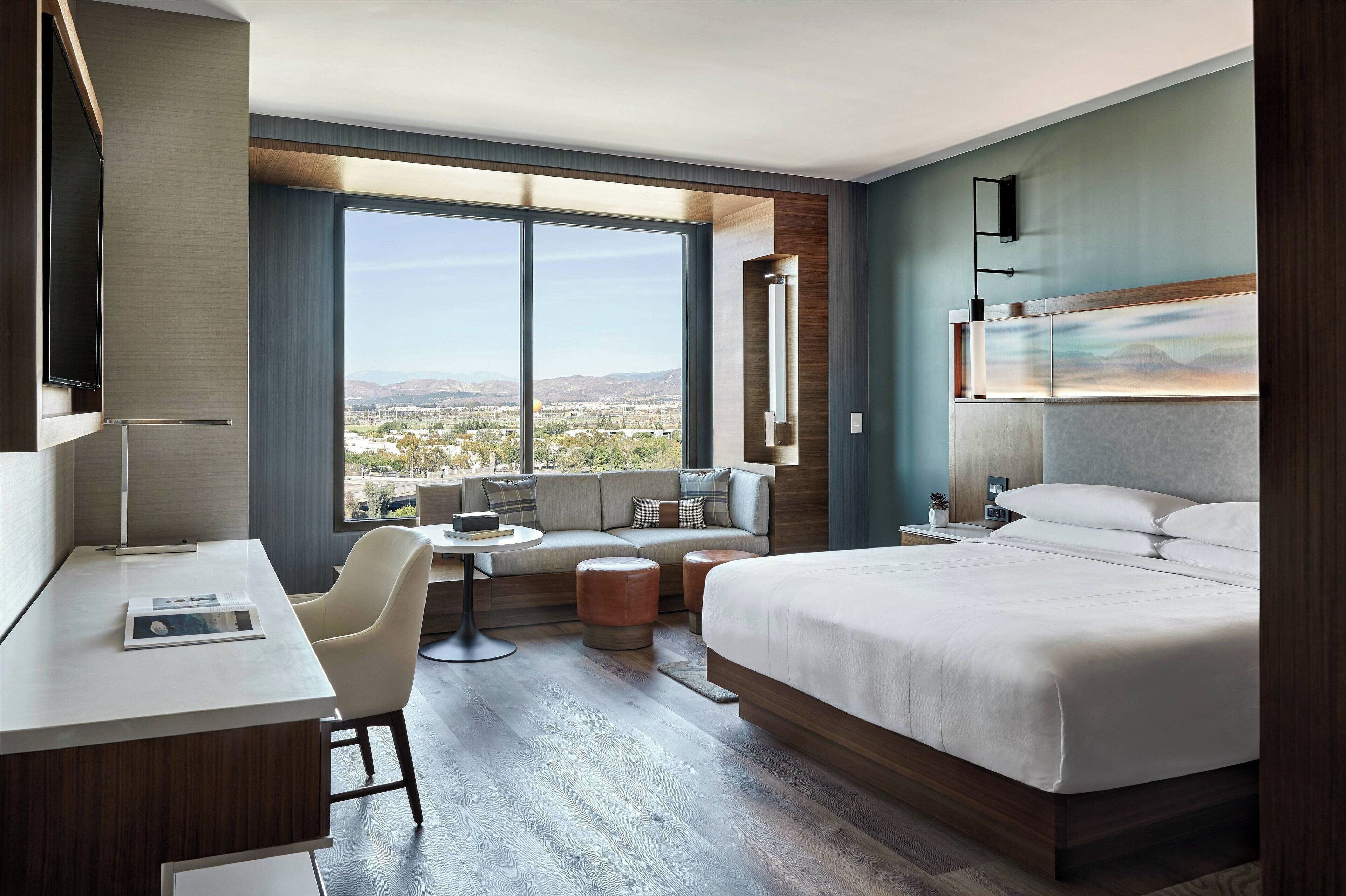 Una habitación de hotel moderna con una cama grande, un escritorio, un sofá y vistas a la ciudad.