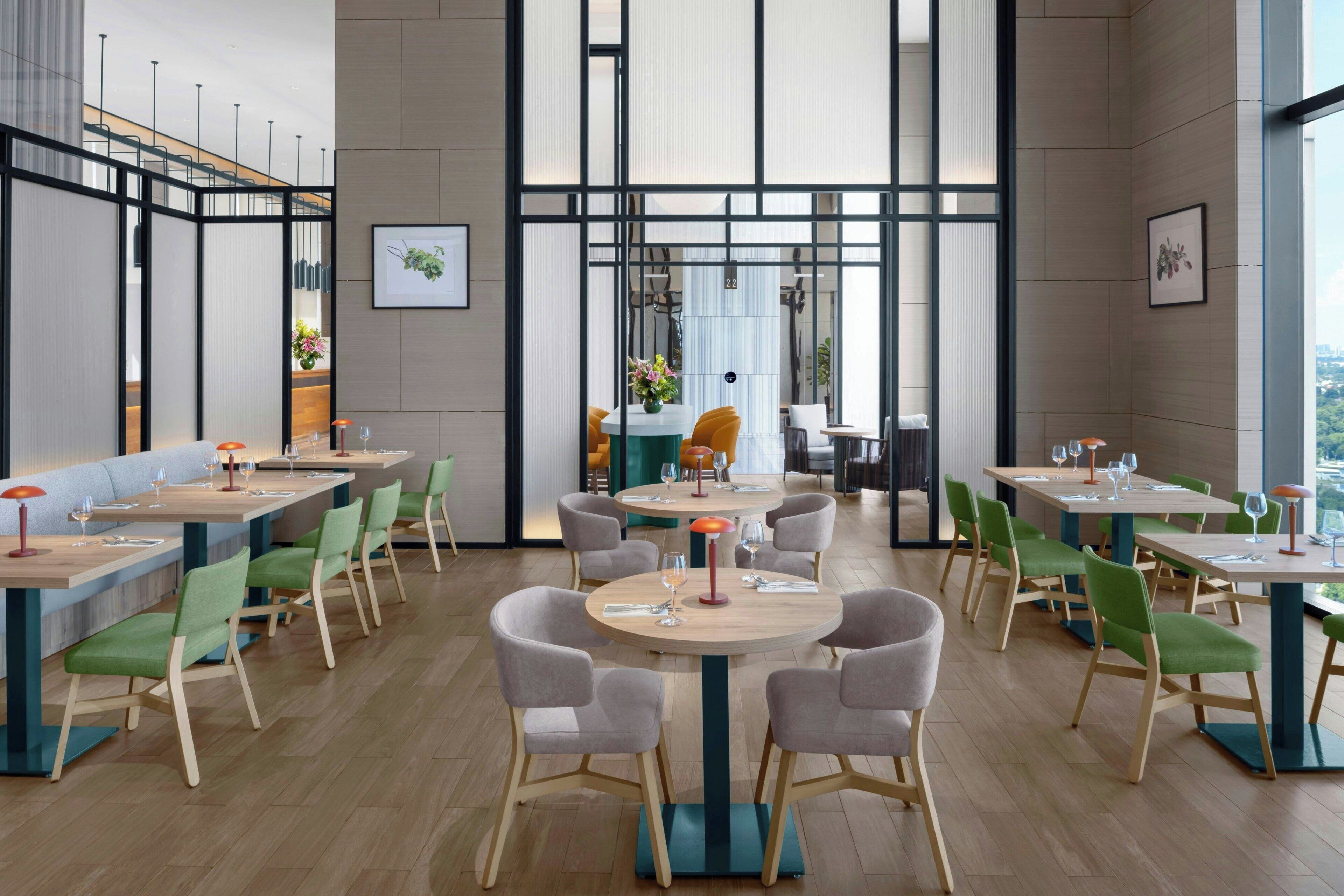 A modern restaurant with multiple dining tables and chairs, featuring a mix of round and rectangular tables.