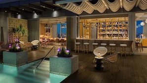 Un espace bar avec une piscine, des sièges et un comptoir.