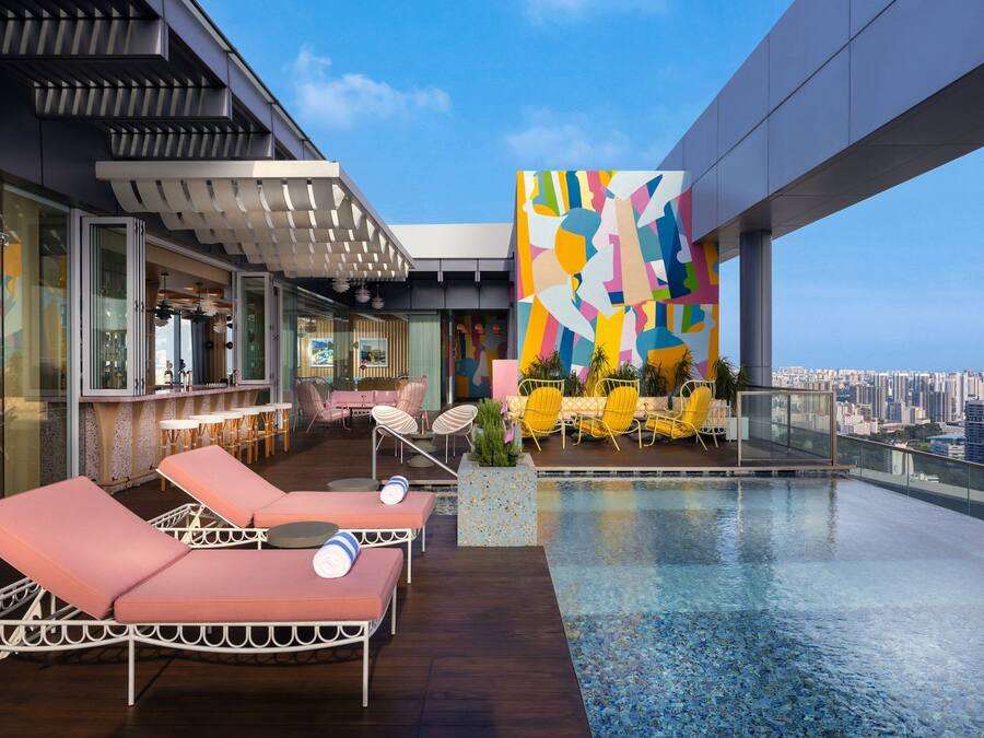 A rooftop pool area with lounge chairs, a bar, and a colorful mural.