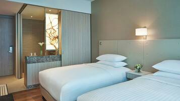 A hotel room with two beds, a bathroom, and a small sitting area.