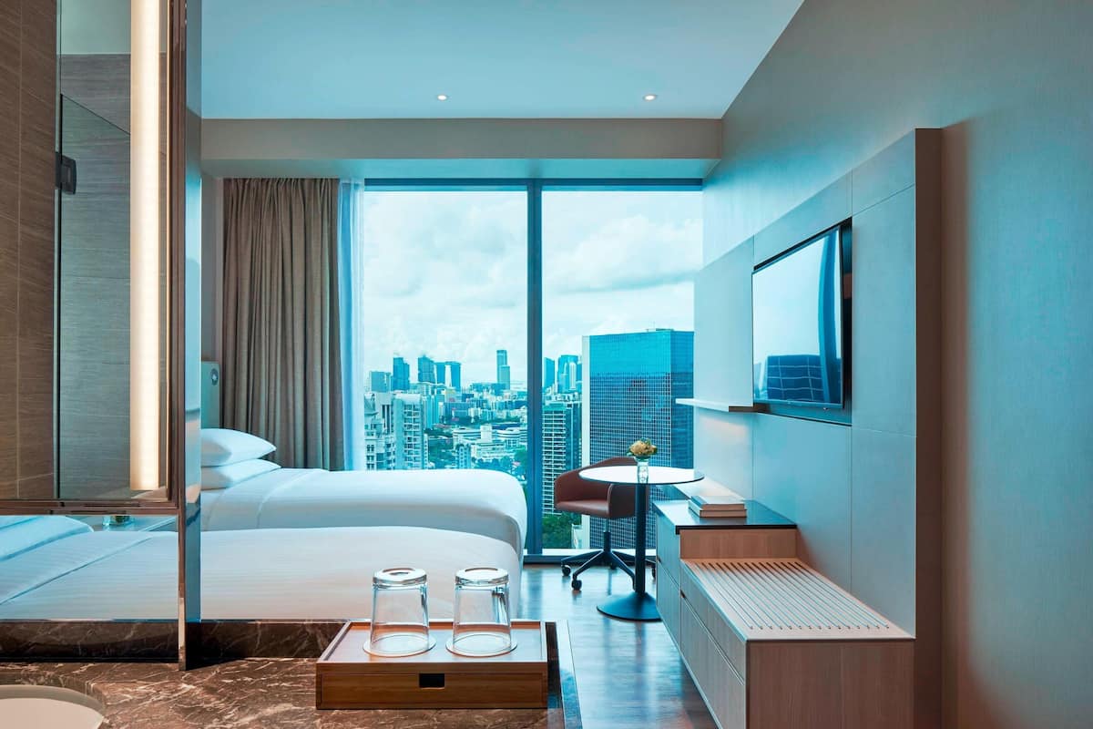 Ein modernes Hotelzimmer mit einem großen Bett, einem Schreibtisch und Blick auf die Stadtlandschaft.