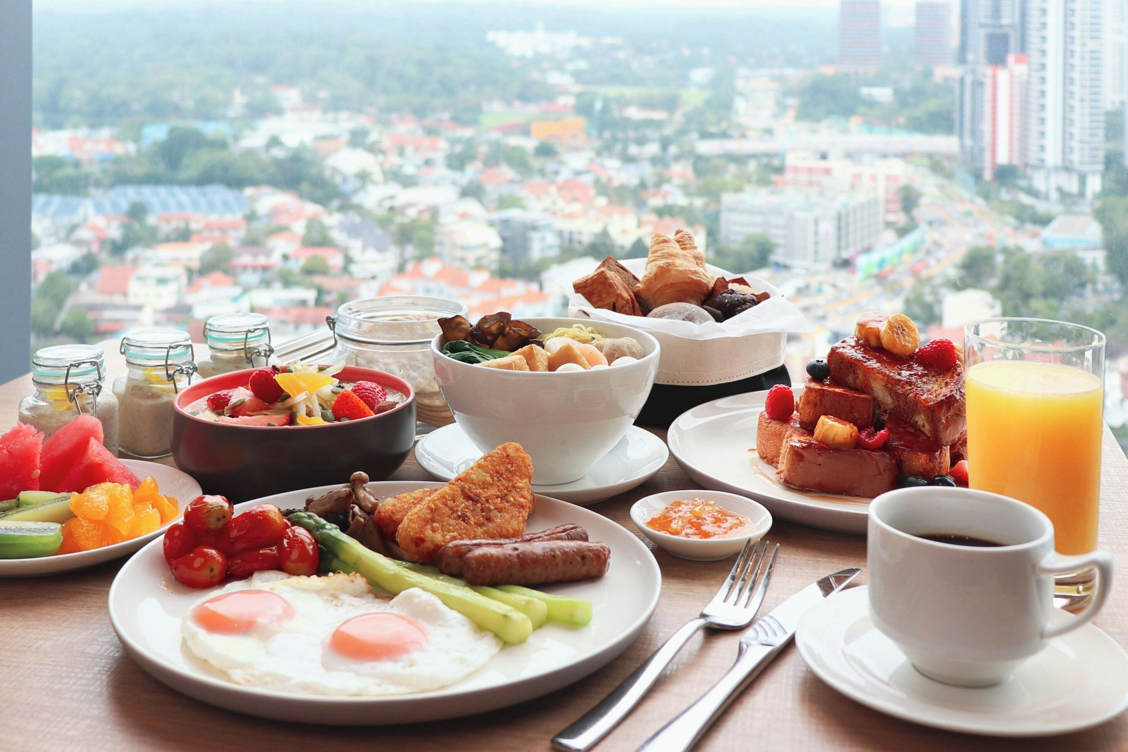 A breakfast table with various dishes, a cup of coffee, and a glass of orange juice.