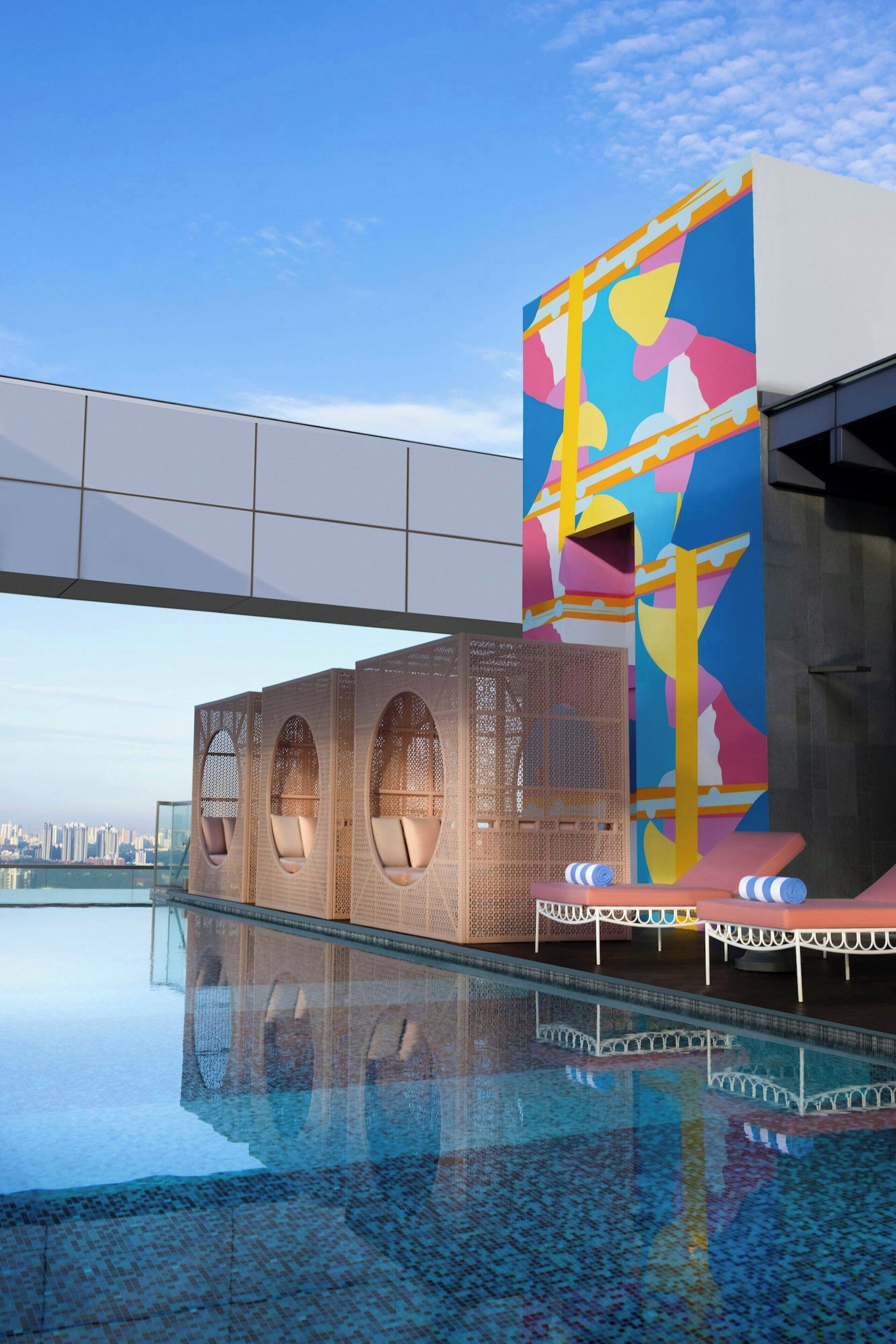 A modern building with a colorful facade, a glass pool, and a cityscape view.