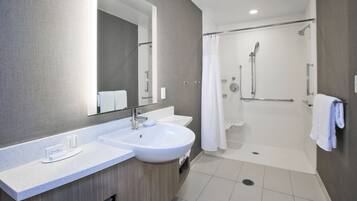 A modern bathroom with a large mirror, two sinks, a shower, and a toilet.