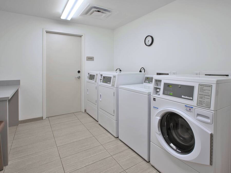 A laundry room with a washing machine, dryer, and a clock on the wall.