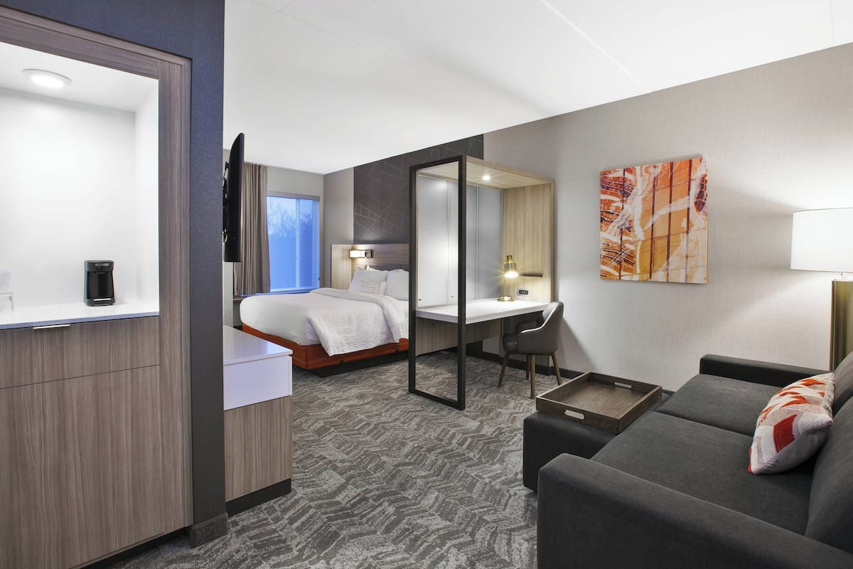 Ein Hotelzimmer mit Bett, Schreibtisch, Sofa, Fernseher und Bad.