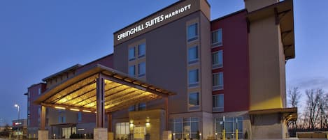 A modern hotel with a covered entrance, multiple floors, and a prominent signage.